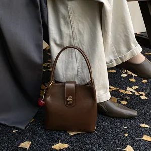 Detailed view of the retro brown leather bucket bag with elegant clasp and cherry charm.