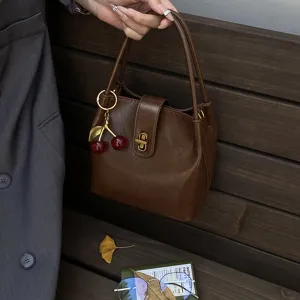 Retro brown bucket bag for women, trendy leather shoulder bag with cute cherry charm and metal lock.