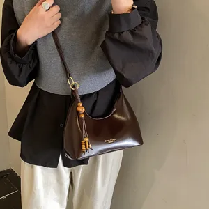 Elegant patent leather hobo shoulder bag with wooden bead tassel charm for women.