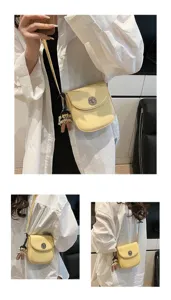 Detail view of mini yellow crossbody phone bag with doll charm, casual style for women.