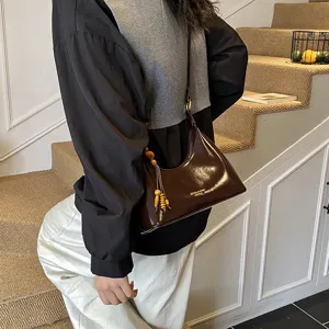 Vintage glossy brown hobo shoulder bag for women with stylish wooden bead tassel charm detail.