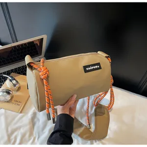 Stylish khaki cylindrical shoulder bag with unique orange rope decor and wide strap for women.