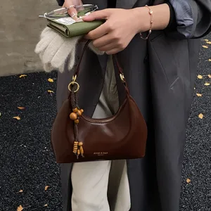 Brown hobo shoulder bag for women, stylish vintage underarm bag with wooden tassel decoration.