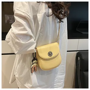 Minimalist women's stylish yellow shoulder crossbody bag with secure lock and cute pendant.