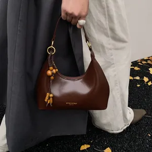 Close-up detail of the retro brown leather hobo shoulder bag with wooden bead charm and gold hardware.