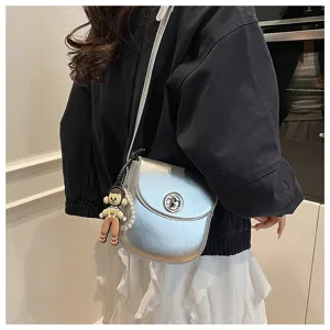 Minimalist silver crossbody bag detail view, sleek metallic twist lock and cute doll keychain.