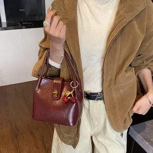 Chic vintage red leather bucket bag with cute cherry charm, stylish shoulder bag for women.