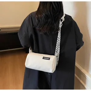 Detail view of stylish white cylindrical shoulder bag with black and white strap.