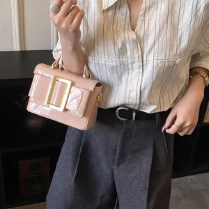 Detail view of pink patent leather handbag with gold metal buckle, stylish daily accessory.