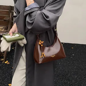 Brown patent leather hobo underarm bag with unique wooden bead charm for daily women fashion.