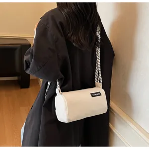Detailed shot of a stylish white cylindrical crossbody bag worn by a model, casual trend.