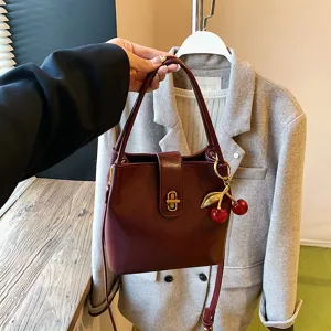 Stylish women wine red bucket bag with cute cherry pendant for casual daily wear and fashion.