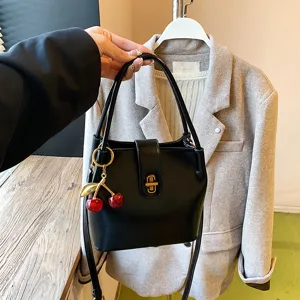 Stylish black bucket bag for women, featuring chic cherry charm and elegant gold hardware.