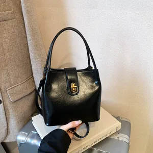 Detail view of stylish black bucket bag featuring gold-tone hardware and classic design.