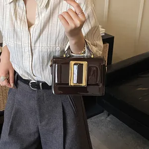 Close-up of a stylish patent leather handbag with a gold-tone buckle, elegant and trendy.