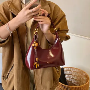 Elegant wine red patent leather underarm shoulder bag with chic wooden bead pendant charm.