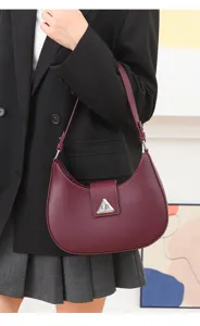 Chic minimalist wine red crescent shoulder bag with metallic triangular clasp for women.