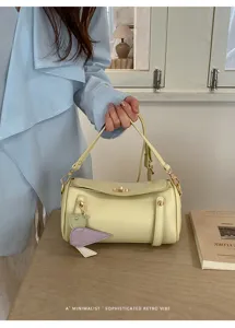 Borsa a spalla cilindrica gialla chic con chiusura metallica e ciondolo per l'estate.