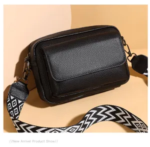 Bolso cruzado de cuero negro con correa ancha geométrica y diseño de múltiples bolsillos.