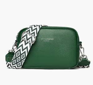 Close-up detail of dark green leather crossbody bag with wide geometric strap and zipper.