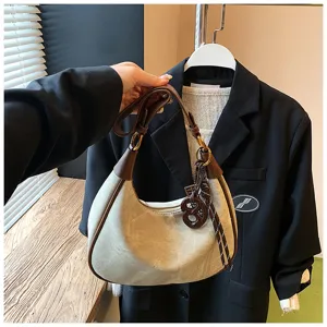 Vista dettagliata della borsa hobo retrò in camoscio con bordi marroni e un ciondolo chic.