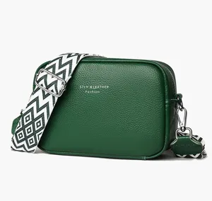 Green genuine leather crossbody bag with wide patterned strap and metal hardware details.