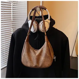 Dettaglio della borsa a tracolla hobo retrò marrone con texture opaca e anelli metallici.