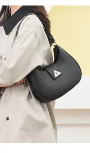 Stylish black crescent shoulder bag for women, minimalist underarm hobo bag with metal clasp.