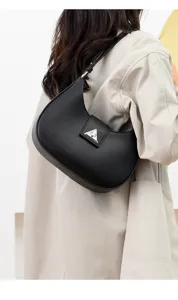 Detailed view of black crescent shoulder bag with metallic triangular buckle and underarm design.