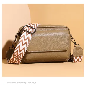 Vista detallada del elegante bolso cruzado de cuero con una correa ancha estampada.