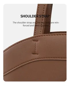 Vue détaillée du sac cabas en cuir marron montrant les coutures renforcées de la bretelle.