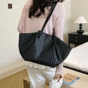 Detailed view of women's black woven shoulder tote bag worn on back, large capacity chic lifestyle