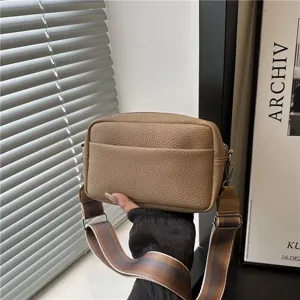 Close-up detail view of a stylish textured PU leather crossbody camera bag with wide woven strap.