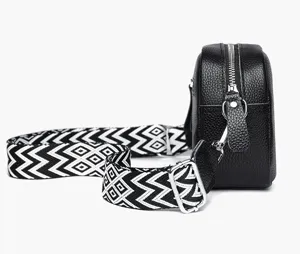 Genuine leather crossbody bag detail, black color with stylish black and white wide strap.