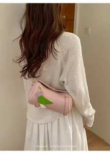 Dettaglio borsa a tracolla cilindrica in pelle rosa con grazioso ciondolo uccello e metalleria.