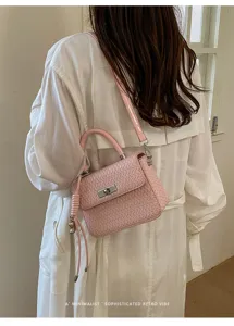 Vista detallada del elegante bolso de hombro rosa tejido con un hermoso cierre metálico.