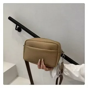 Close-up view of solid color PU leather crossbody shoulder bag detail in casual daily scene.