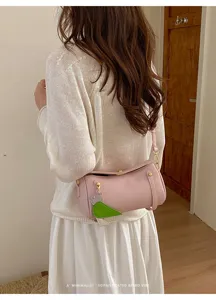 Dettaglio borsa a tracolla cilindrica rosa, stile minimalista retrò con ciondolo.