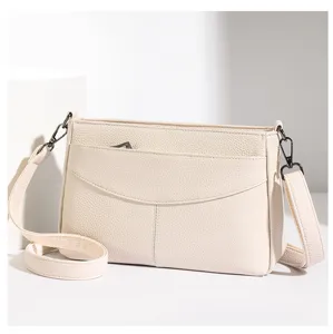 Classic beige leather crossbody shoulder bag featuring front pocket and adjustable strap.