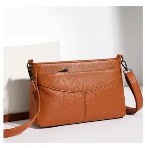 Close-up detail of the brown genuine leather cross-body bag showing fine texture and neat stitching.