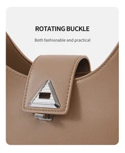Detail view of stylish women's crescent shoulder bag with rotating buckle in camel leather.