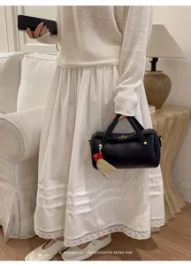 Vista dettagliata della borsa a tracolla nera minimalista con ciondolo uccello chic.
