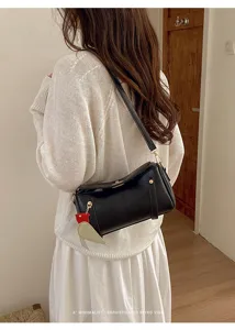Primo piano dettagliato della borsa a tracolla elegante in pelle nera con ciondolo chic.