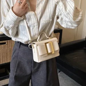 Stylish white leather crossbody bag with bold golden buckle, elegant top handle design for women.