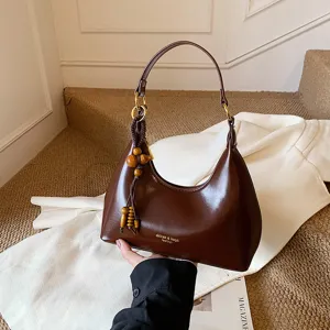 Vintage brown hobo shoulder bag for women with wooden bead charm and stylish crescent design.