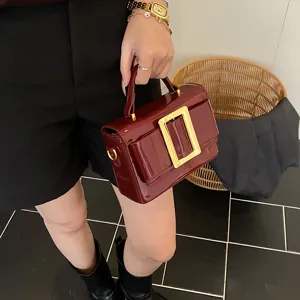 Wine red patent leather retro shoulder bag with bold gold buckle detail, stylish.