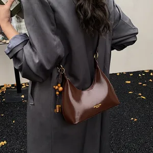 Retro patent leather underarm shoulder bag for women, chic crescent handbag with tassel charm.