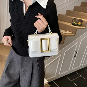 Detailed view of white patent leather shoulder bag with chic gold buckle and top handle.