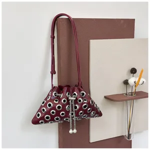 Detailed view of the dark red leather grommet bucket bag with pearl chain and metal eyelets.