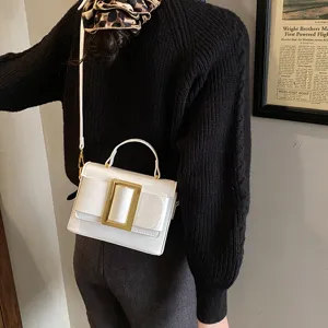 Close-up detail of a chic white retro shoulder bag with a bold gold buckle and sleek strap.